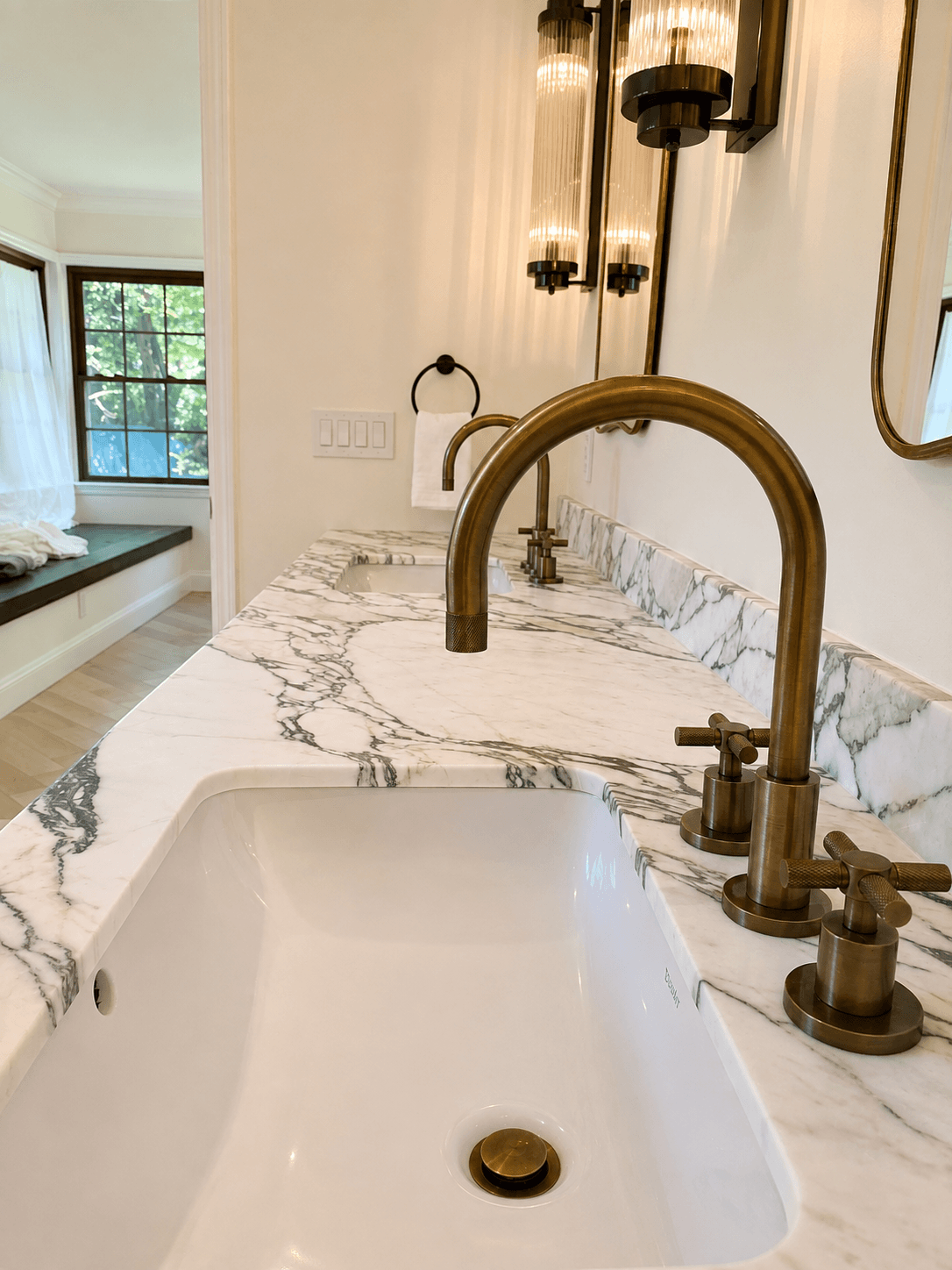 Marble vanity countertop with undermount sink cutout and brass fixtures
