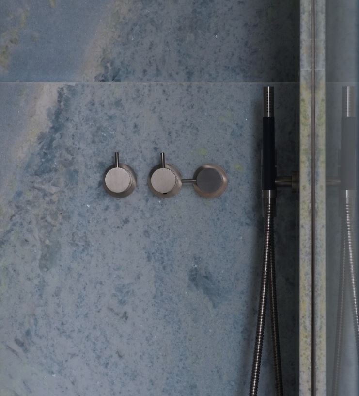Shower valve and handheld sprayer set into Blue Celeste marble walls